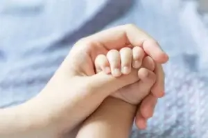 תינוקת מחזיקה את ידה של אמא שלה בבריתה.צולם על ידי צלם לבריתה של מגנטסטאר צילום אירועים