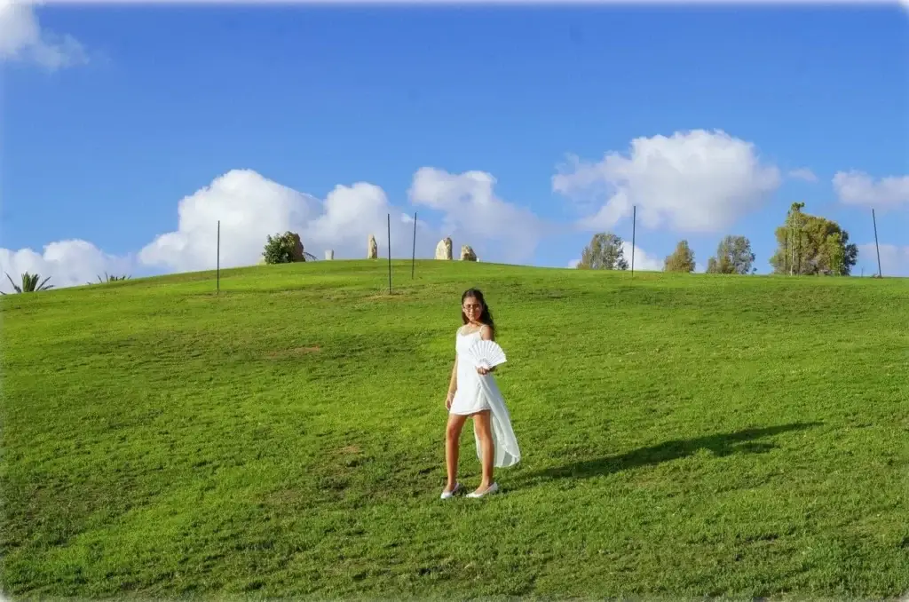 ילדת בת מצווה מצטלמת בשמלה לבנה באמצע גבעת דשא. צולם לבוק בת מצווה על ידי צלם לבת מצווה של מגנטסטאר צילום אירועים.