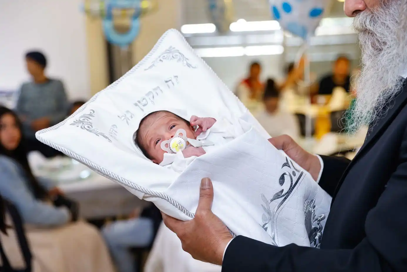 רב מחזיק תינוק בכרית לפני הברית מילה. צולם על ידי צלם לברית מילה. תחת קטגוריית צלם לברית של מגנטסטאר צילום אירועים