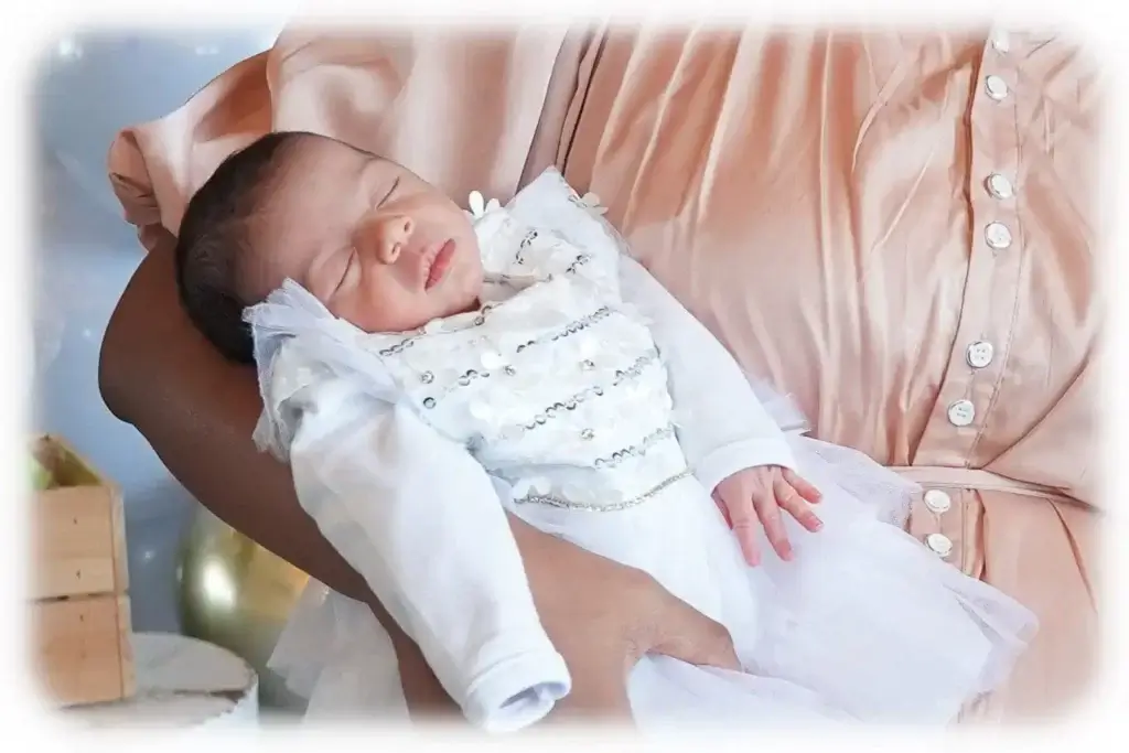 תינוקת ישנה על ידיים של אישה דתיה. צולם על ידי צלם לבריתה של מגנטסטאר צילום אירועים