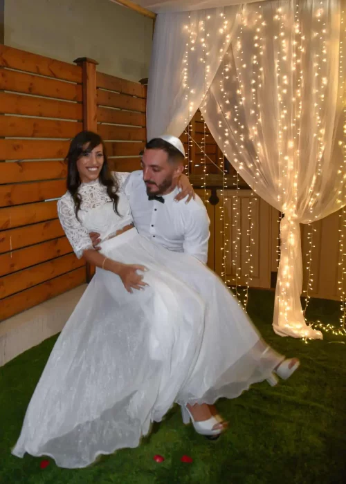 החתן מרים את הכלה בצילום חתונה ביתית. צולם על ידי צלם סטילס לחתונה. תחת קטגוריית צלם חתונות של מגנטסטאר צילום אירועים
